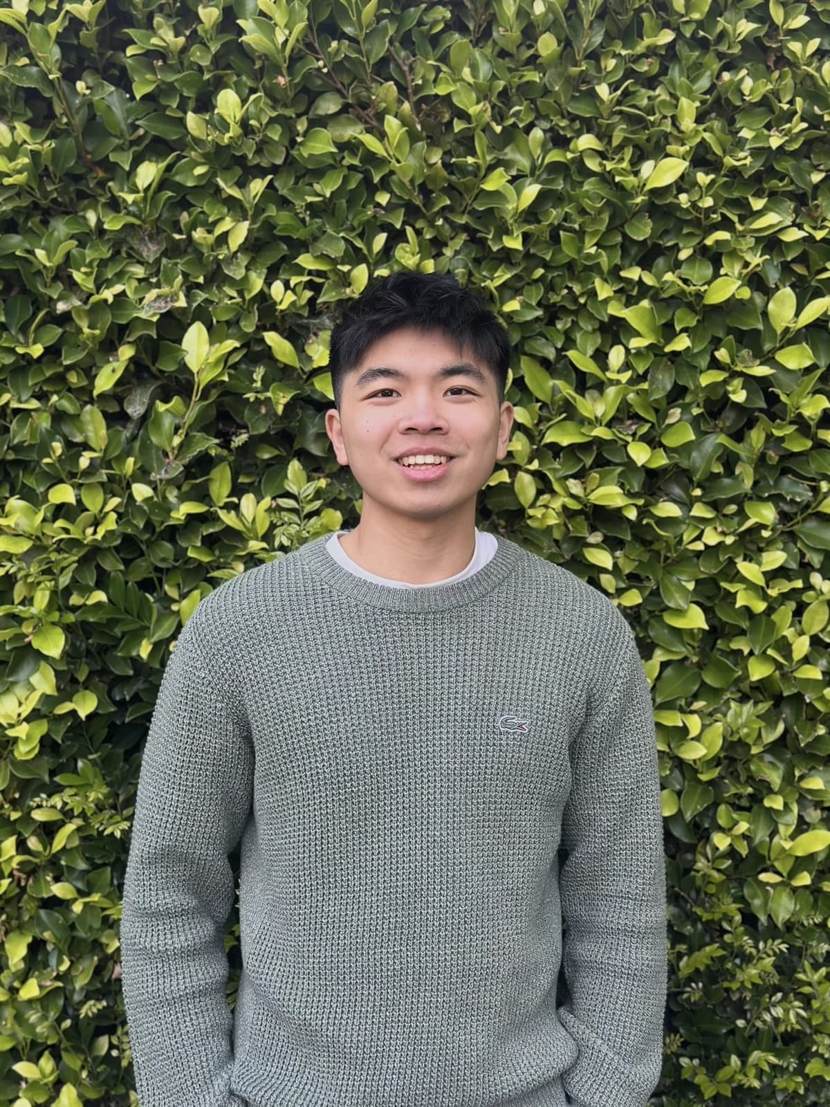 Dayrent standing in front of a leafy green hedge