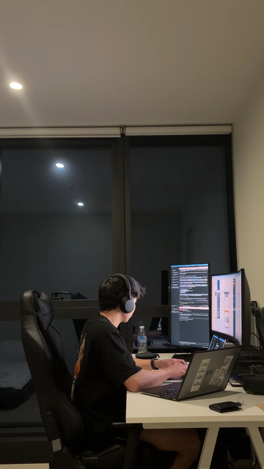 Dayrent wearing headphones while coding at a desk at night